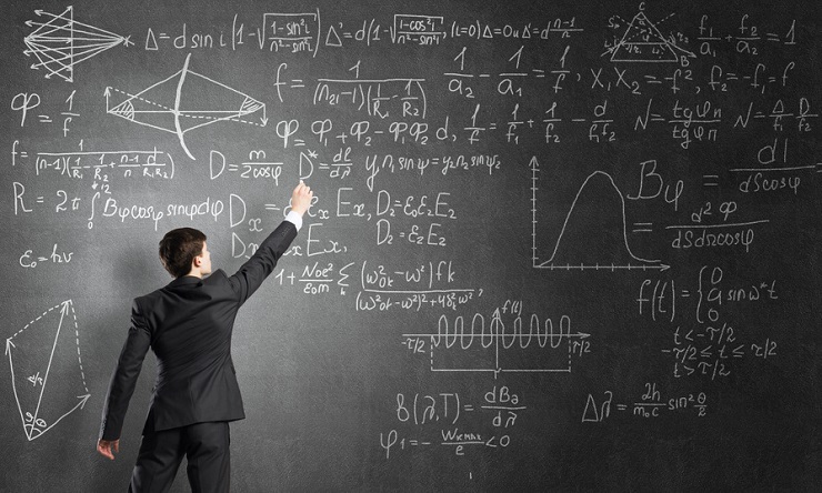 Man in suit standing with back and drawing formulas on chalkboard