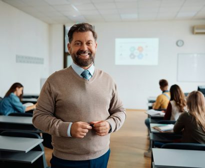 Happy university teacher in the classroom looking at camera.